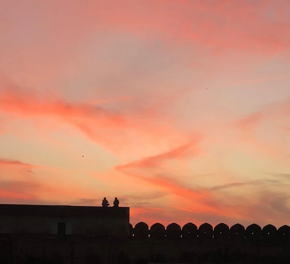 Silhouette of a fort wall against a fiery sunset sky