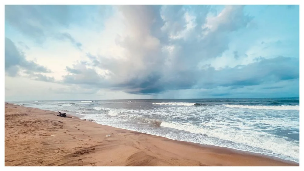 Waves rolling onto a sandy beach under a cloudy sky